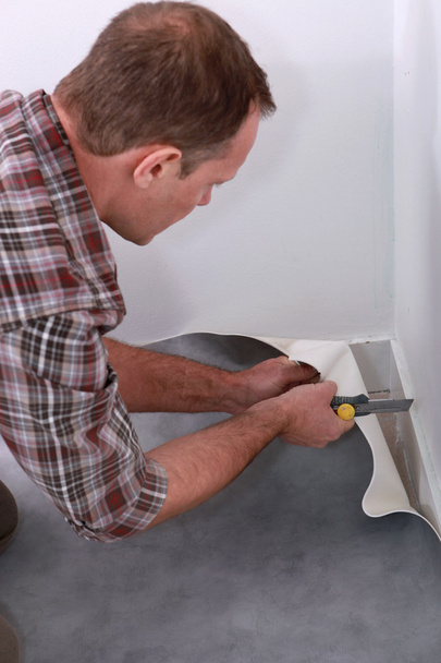 Handyman cortar pisos de linóleo para adaptarse a una esquina de una habitación
 - Foto, imagen