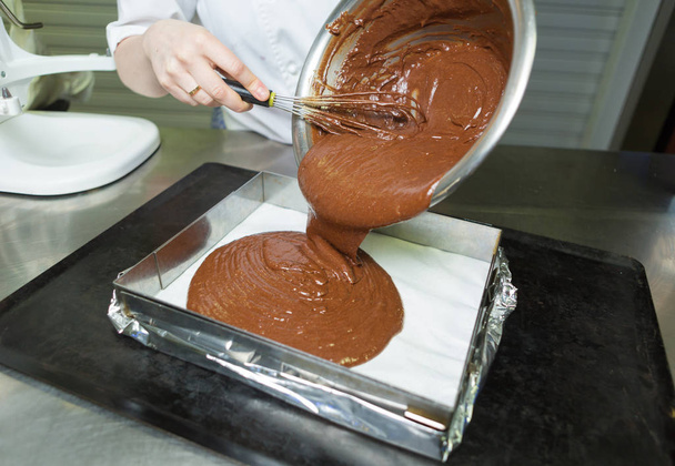 Creamy rich dark chocolate dessert sauce being poured into a baking tray. - Foto, Imagem