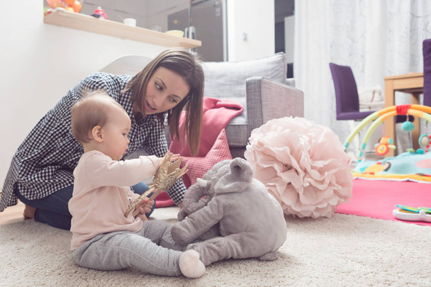 Nine months old baby girl playing with her mother on the floor - Fotoğraf, Görsel