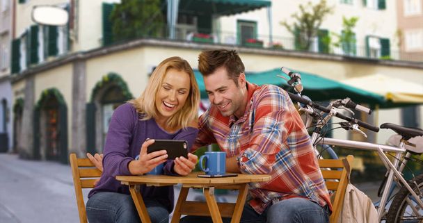 White millennial couple laughing and having a good time outside a coffee shop - Photo, Image