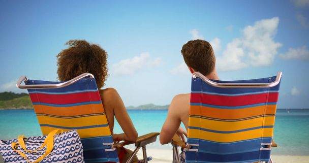 Close-up van paar zittend op strandstoelen water horizon kijken. - Foto, afbeelding