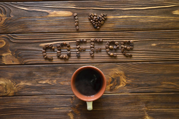 Я люблю каву, написану кавовими зернами на дерев'яному столі. Кава, написана з кавовими зернами на столі
. - Фото, зображення