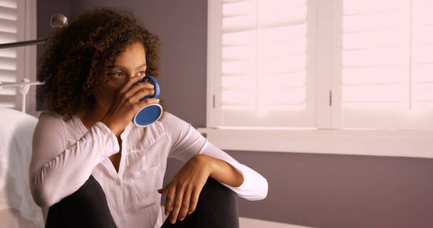 Düşünme ve kahve bardağı içme çekici genç siyah kadın. - Fotoğraf, Görsel