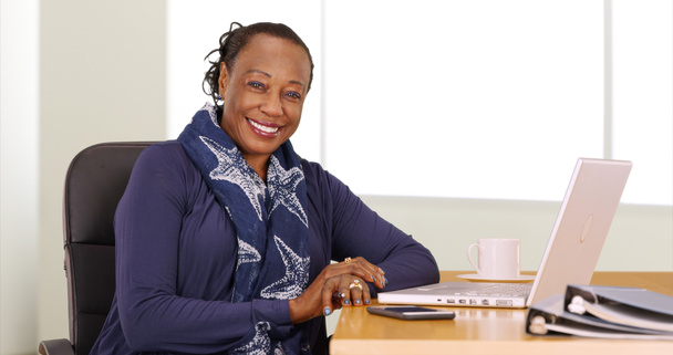 A black businesswoman poses for a portrait at her desk - Photo, Image