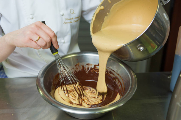 Molho de toffee salgado cremoso sendo misturado e misturado, em uma tigela de rico molho de chocolate escuro
. - Foto, Imagem