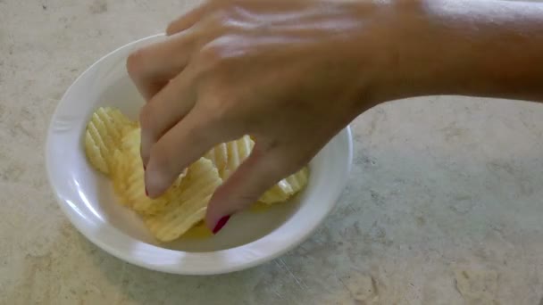 Female hand takes the chips from the bowl till it is empty - Materiał filmowy, wideo