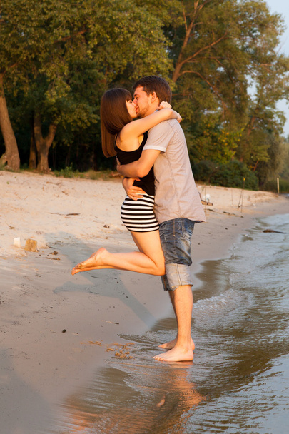 Пара обіймає і цілується на березі річки
 - Фото, зображення