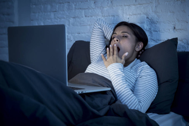 Nuori kaunis latino internet addikti nainen sängyssä tietokoneen kannettava tietokone haukottelu väsynyt
 - Valokuva, kuva