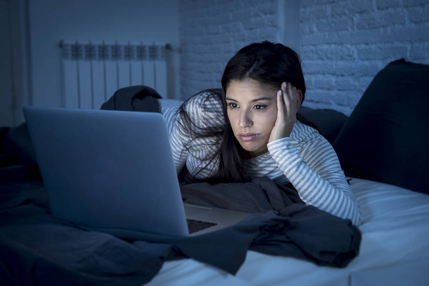 Frau im Schlafanzug auf dem Bett zu Hause Schlafzimmer arbeiten gelangweilt und müde mit Laptop-Computer - Foto, Bild
