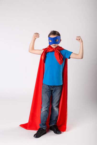 Divertido niño superhéroe muestra su músculo
 - Foto, imagen