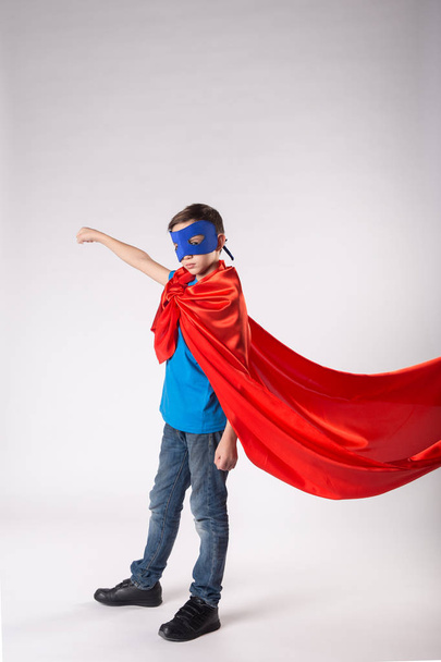 Super herói miúdo de capa vermelha a tremer no vento
 - Foto, Imagem