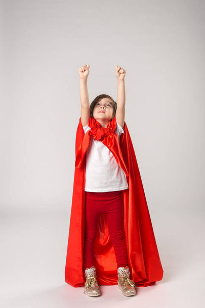 Superheldenmädchen in rotem Umhang hob die Hände - Foto, Bild