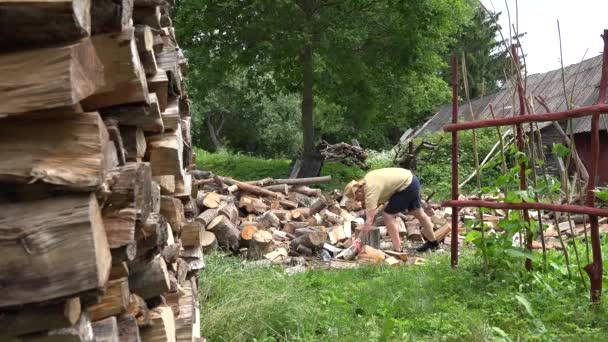 Ein Bauer in kurzen Hosen bereitet Brennholz zu. 4k - Filmmaterial, Video
