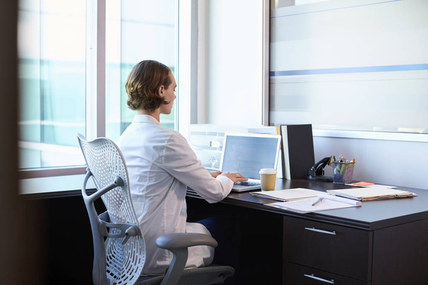 Γιατρός φοράει λευκό παλτό που εργάζονται στο γραφείο - Φωτογραφία, εικόνα