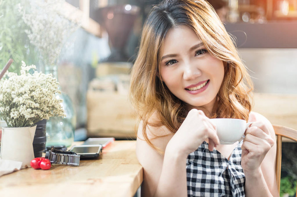 asain beauty girl happy in checker dress smiling with hot cofee in coffee shop - Zdjęcie, obraz