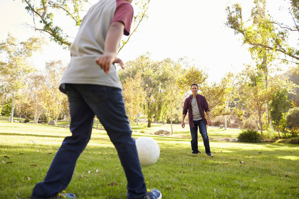boy kicking ball to dad  - Foto, afbeelding