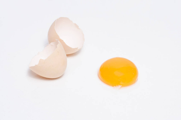 Яйца цыпленка с яичным желтком и скорлупа на сером фоне
 - Фото, изображение