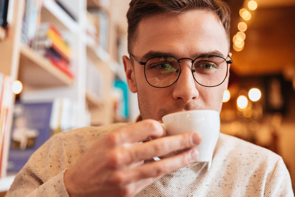 Handsome young man drinking coffee and look aside. - Fotoğraf, Görsel