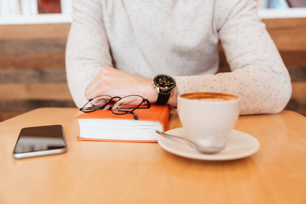 Cropped photo of man in cafe with coffee and book. - Foto, Imagen