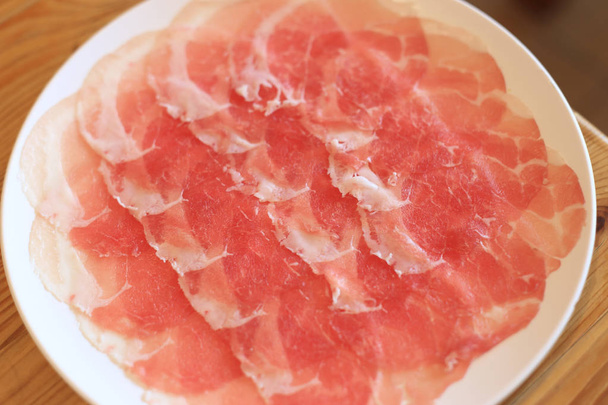 Carne di maiale cruda affettata in piatto bianco per shabushabu, ricetta giapponese
. - Foto, immagini