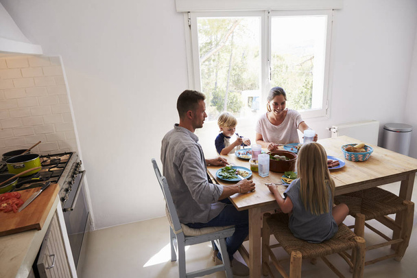 Family eating at table in sunlit room - Zdjęcie, obraz