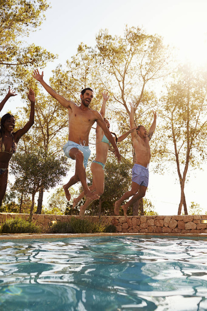 Young friends jumping into pool - Foto, Bild