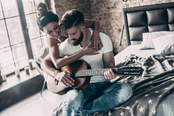 couple with acoustic guitar in bed - Foto, imagen