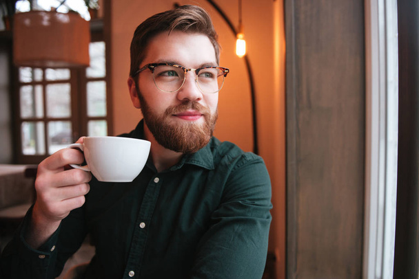 Handsome bearded young man drinking tea. - 写真・画像