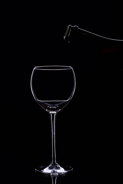 Wine glasses with wine bottle on a black background, minimalism, - Foto, afbeelding
