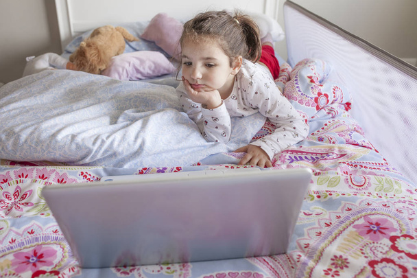 Malá holčička sledování filmů s notebookem v posteli - Fotografie, Obrázek