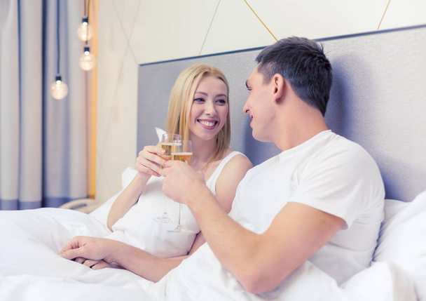 smiling couple with champagne glasses in bed - 写真・画像