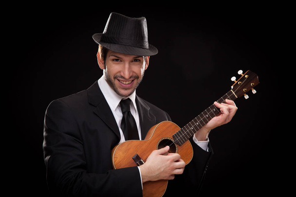 elegant happy man singer musician playing ukulele guitar isolated on black - 写真・画像