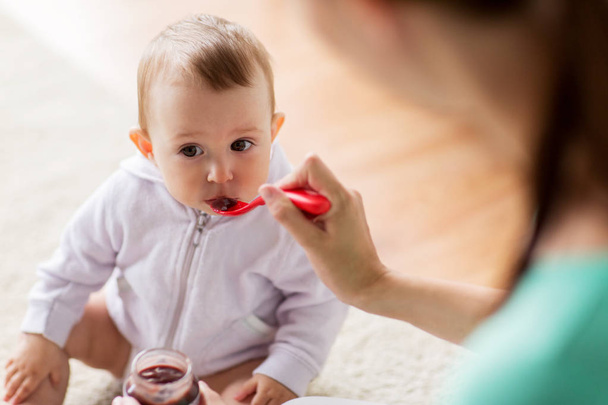 mother with spoon feeding little baby at home - Foto, Bild