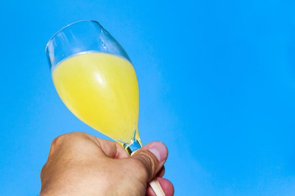 Holding a glass of champagne mixed with orange juice against blu - Photo, Image