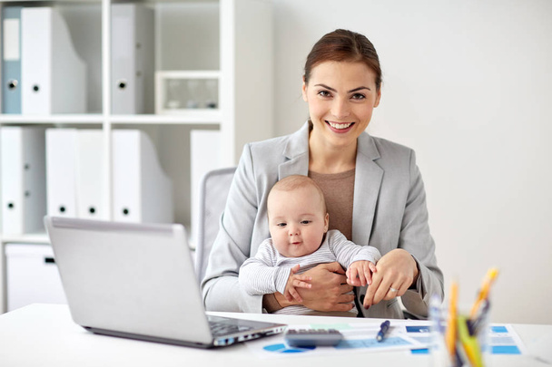 happy businesswoman with baby and laptop at office - 写真・画像