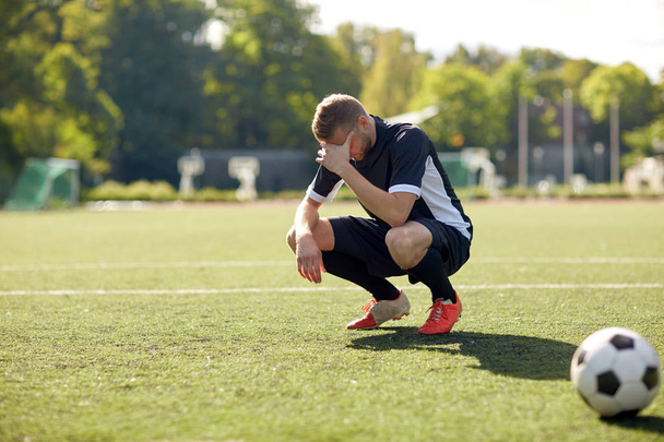 сумний футболіст з м'ячем на футбольному полі
 - Фото, зображення