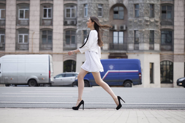 Young beautiful brunette woman in white dress walking on the str - Photo, image