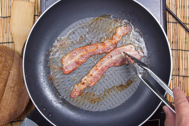 Chef frying bacon in the pan - Photo, Image