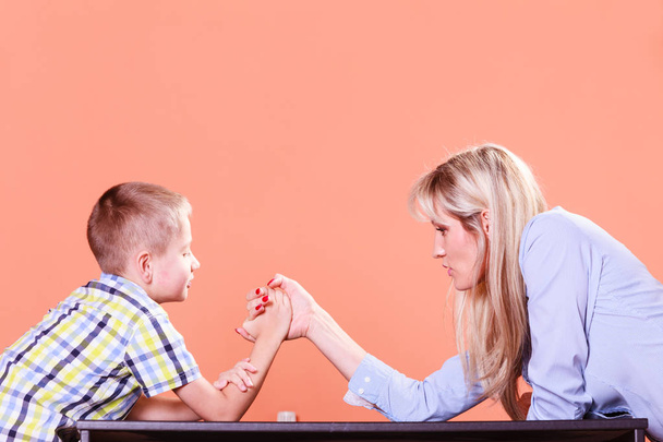 Mother and son arm wrestle sit at table. - Photo, image