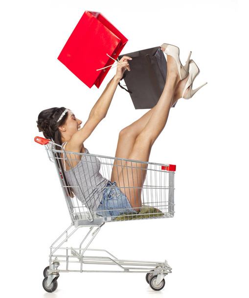 Young beautiful brunette girl sits in an empty shopping cart wit - Foto, Bild
