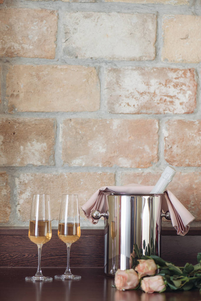 Пара склянки шампанського з пляшкою в металевій тарі. Елегантний інтер'єр готельного номера
.  - Фото, зображення