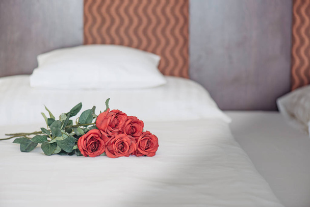 Τριαντάφυλλα σε κρεβάτι σε φανταχτερό ξενοδοχείο δωμάτιο - Φωτογραφία, εικόνα