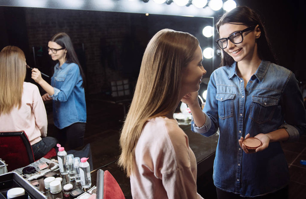 Cute happy makeup artist putting on cosmetic powder - Photo, image