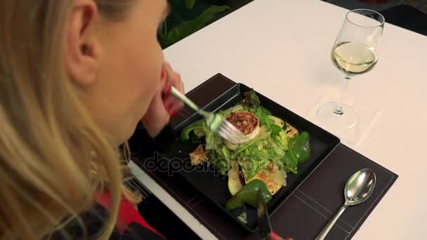 Egy nő ül egy asztalnál, egy étteremben, és eszik egy saláta - Felvétel, videó