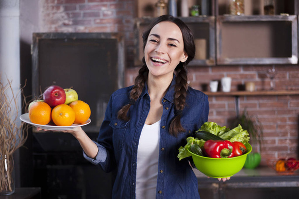 Young Woman in the kitchen. Healthy Food. Dieting Concept. Healthy Lifestyle. Cooking At Home. Prepare Food. Very Beautiful cheerful young brunette woman holding fruits and vegetables and smiling. - Φωτογραφία, εικόνα