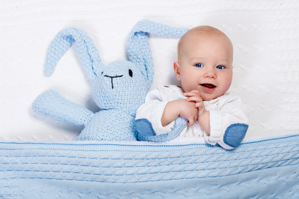 Bébé garçon jouer avec lapin jouet dans le lit
 - Photo, image