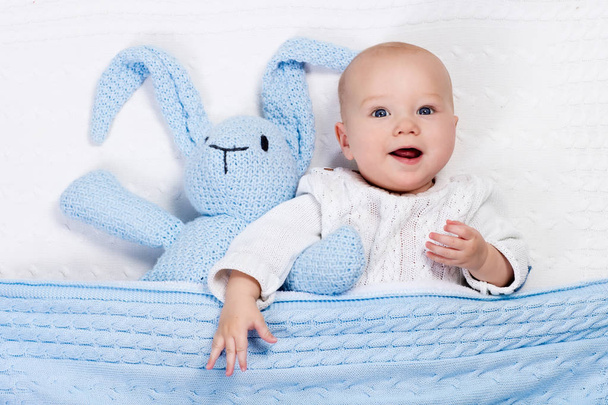 Bebé niño jugando con conejo juguete en la cama
 - Foto, imagen