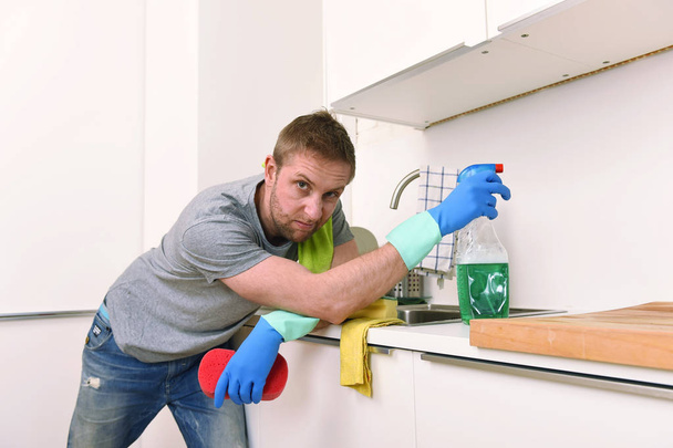 молодой грустный разочарованный мужчина стирает и убирает домашнюю раковину кухни
 - Фото, изображение
