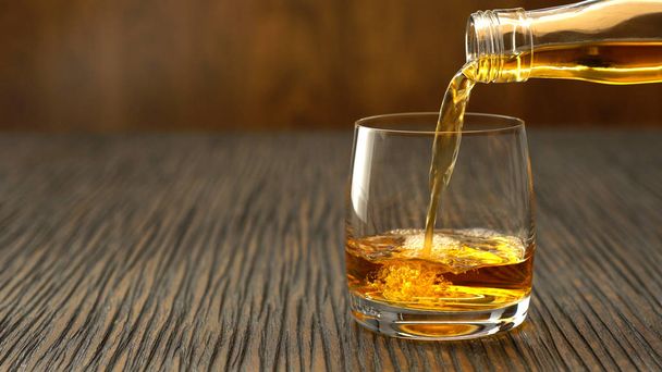 Whisky auf einem Holztisch ins Glas gießen - Foto, Bild
