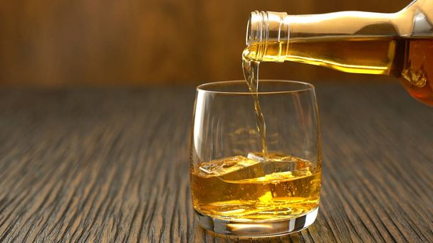 Nalil whisky do sklenice na dřevěný stůl - Fotografie, Obrázek
